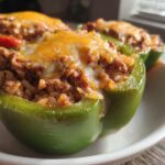 Close-up of Cheesy Ground Beef Stuffed Peppers, featuring green and red peppers filled with meat and rice, topped with melted cheese.