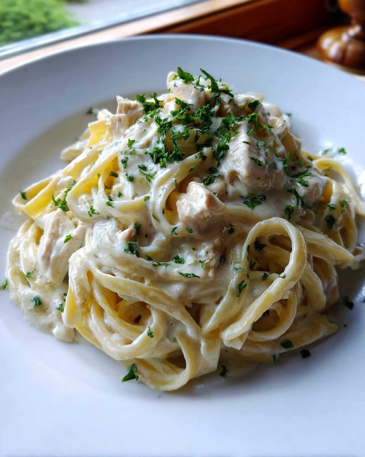 A close-up of a serving of Creamy Alfredo Chicken Pasta Easy Recipe, topped with fresh parsley.