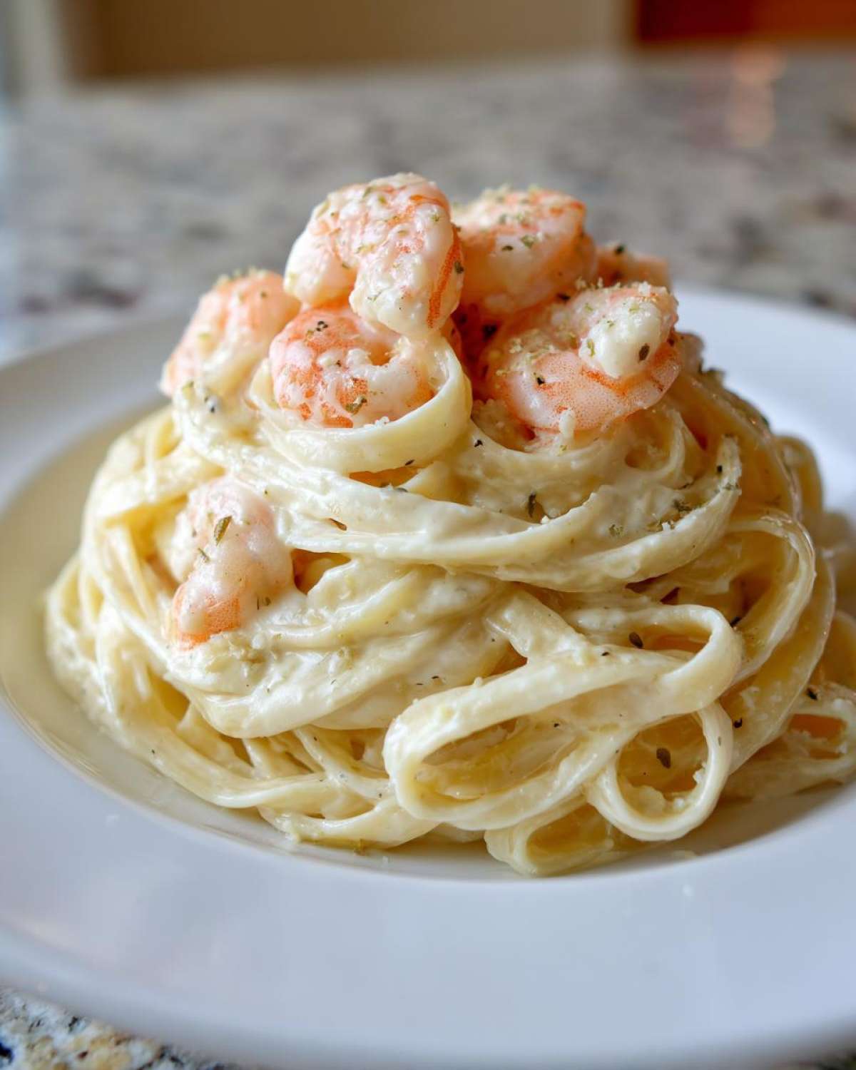 A close-up of Creamy Alfredo Shrimp Pasta with Garlic, featuring fettuccine coated in rich sauce and topped with pink shrimp.