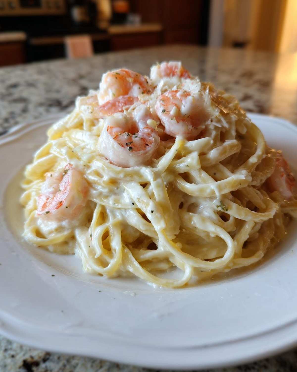 Close-up of a serving of Creamy Alfredo Shrimp Pasta with Garlic, featuring fettuccine coated in rich white sauce and topped with pink shrimp.