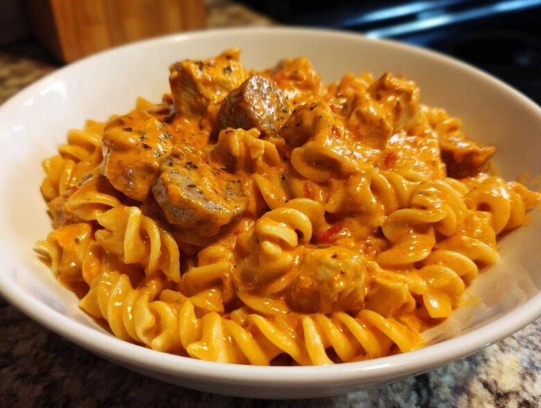 A close-up of Creamy Cajun Chicken Pasta featuring rotini/fusilli pasta coated in a rich, orange-hued sauce with chunks of seasoned chicken.
