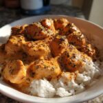 Close-up of Creamy Cajun Chicken Skillet with Rice, featuring chicken pieces in a rich orange sauce over white rice.