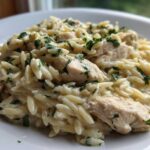 Close-up of a serving of Creamy Garlic Parmesan Orzo with Chicken, topped with fresh parsley.