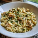 A close-up of a white bowl filled with Creamy Lemon Chicken Orzo with Fresh Herbs, topped generously with chopped parsley.