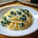 A close-up of Creamy Lemon Ricotta Pasta with Spinach, tossed in a light sauce and topped with grated cheese.
