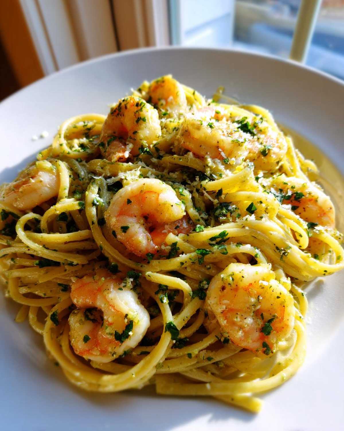 A close-up of a serving of Creamy Lemon Shrimp Pasta with Garlic Sauce, topped with shrimp and parsley.