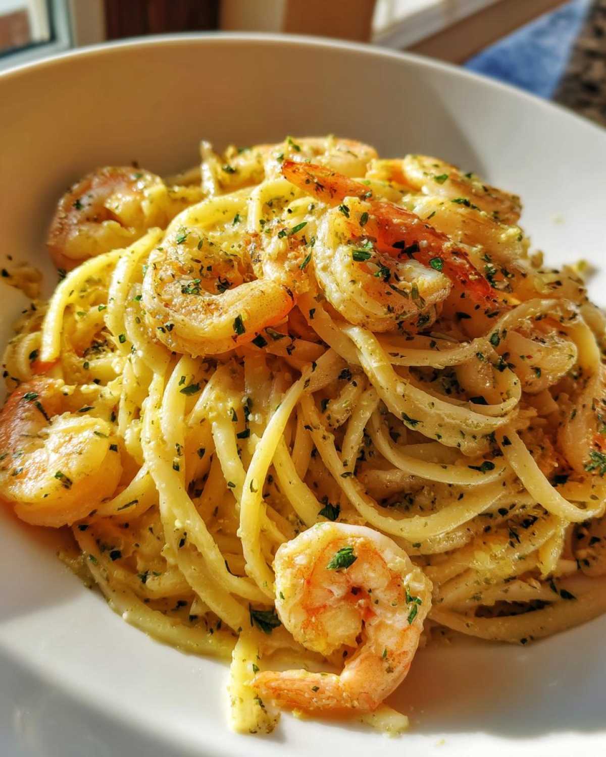 Close-up of a bowl filled with Creamy Lemon Shrimp Pasta with Garlic Sauce, topped with seasoned shrimp and parsley.