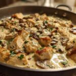 Close-up of seared chicken pieces and sliced mushrooms coated in a rich, creamy sauce in the Creamy Mushroom Alfredo Chicken Skillet.