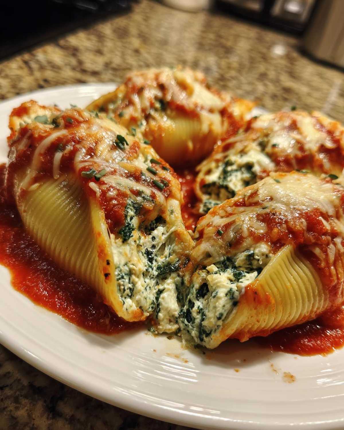 Four baked stuffed pasta shells filled with creamy spinach and ricotta, topped with marinara sauce and melted cheese.