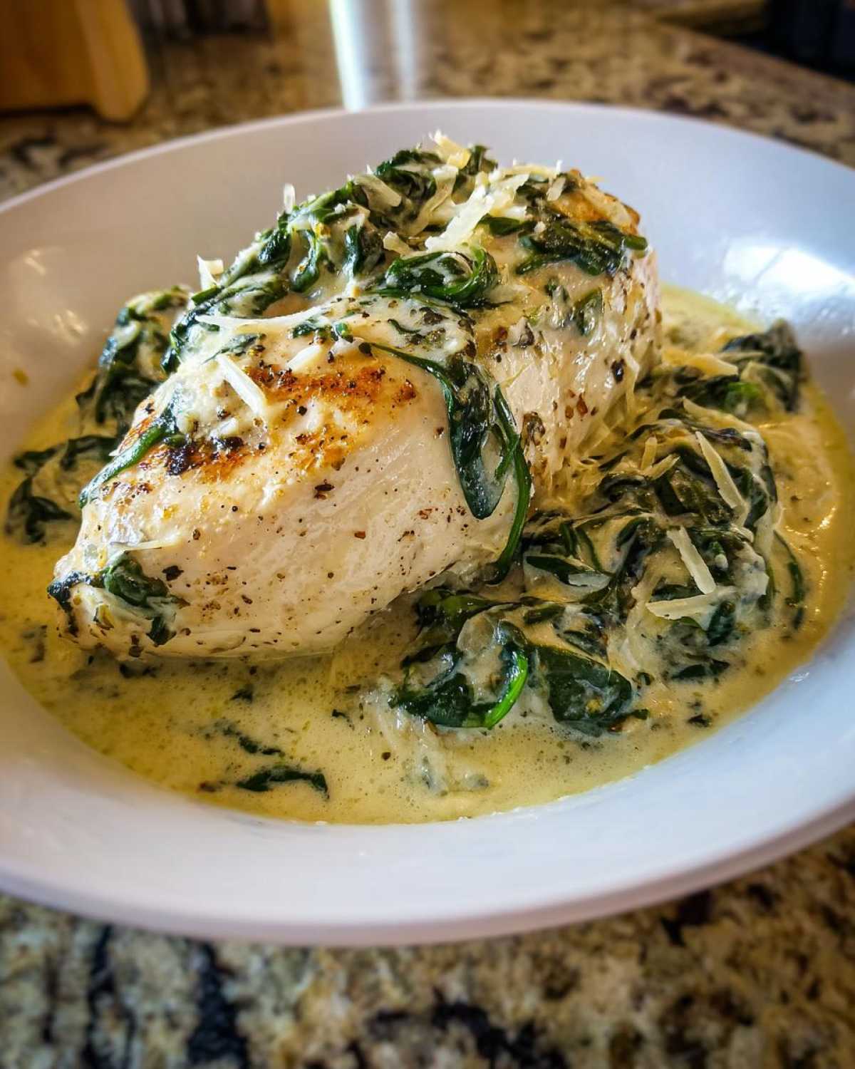 A perfectly cooked chicken breast smothered in creamy spinach ricotta sauce and topped with Parmesan cheese.
