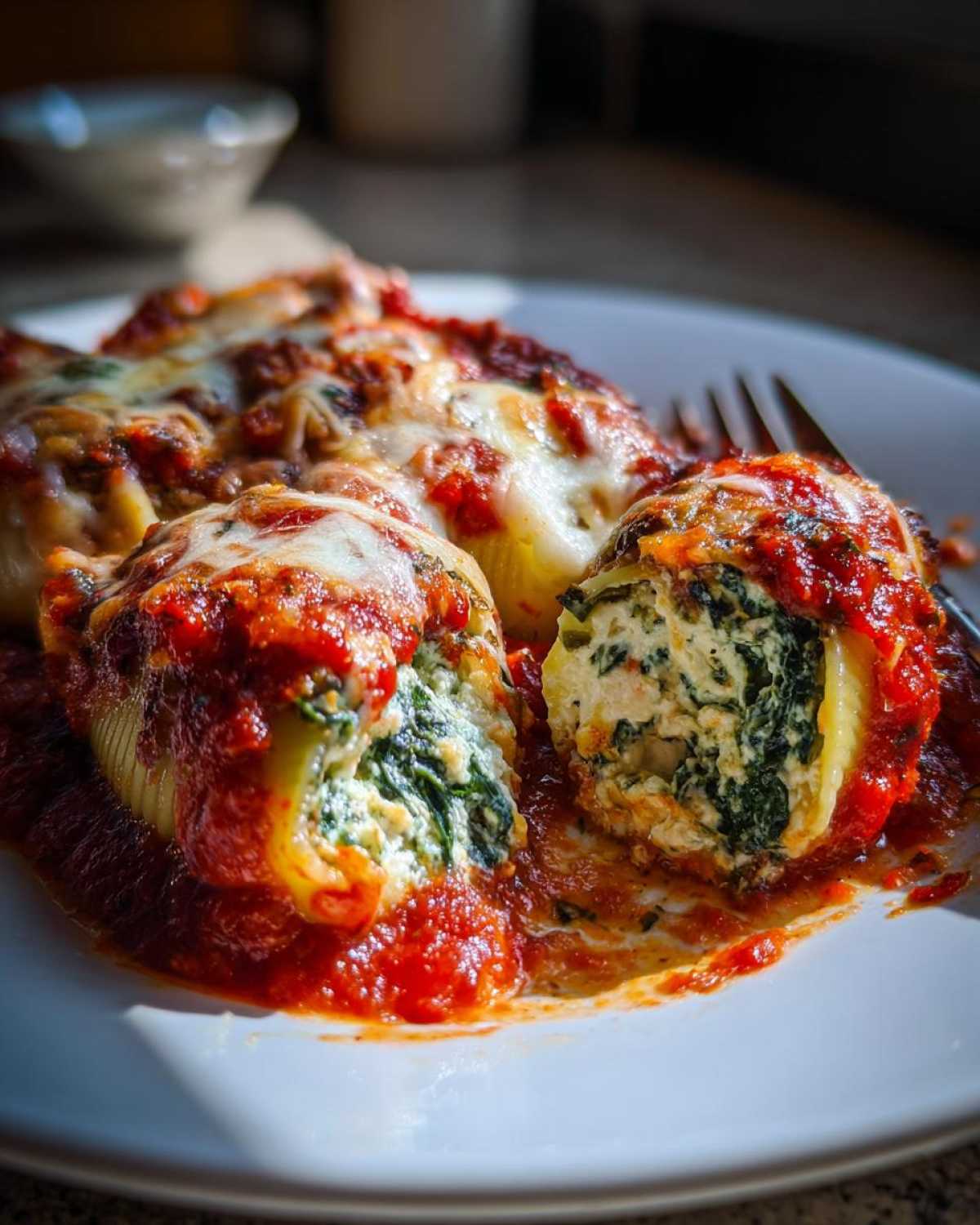 A close-up view of baked Creamy Spinach and Ricotta Stuffed Shells covered in marinara sauce and melted cheese.