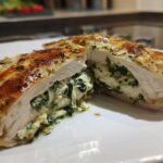 Cross-section view of a golden-brown Creamy Spinach Stuffed Chicken Breast, revealing the rich filling.