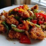 Close-up of Crispy Chicken Fajitas with vibrant sautéed peppers, onions, and a savory sauce on a white plate.