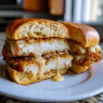 Cross-section of a Crispy Chicken Sandwich with Garlic Parmesan Sauce dripping over thick chicken breast.