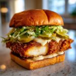 A thick, juicy Crispy Chicken Sandwich with Garlic Sauce, topped with pickles and slaw on a toasted brioche bun.