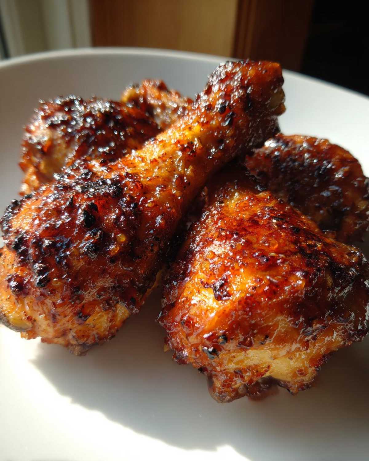 Close-up of three oven-baked Crispy Honey Garlic Chicken Drumsticks with a sticky, caramelized glaze.