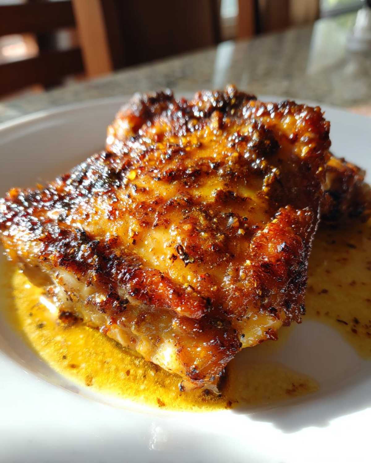 Close-up of a perfectly cooked Garlic Butter Chicken Thighs with incredibly crispy, seasoned skin resting in its rendered butter sauce.