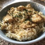 Close-up of Garlic Butter Chicken and Rice One Pot Dinner served in a light blue bowl, topped with parsley.