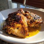 Three perfectly cooked Garlic Butter Chicken Thighs with crispy, browned skin resting in a pool of melted butter sauce.