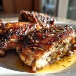 Close-up of three perfectly cooked Garlic Butter Chicken Thighs with crispy, herb-crusted skin resting in butter sauce.