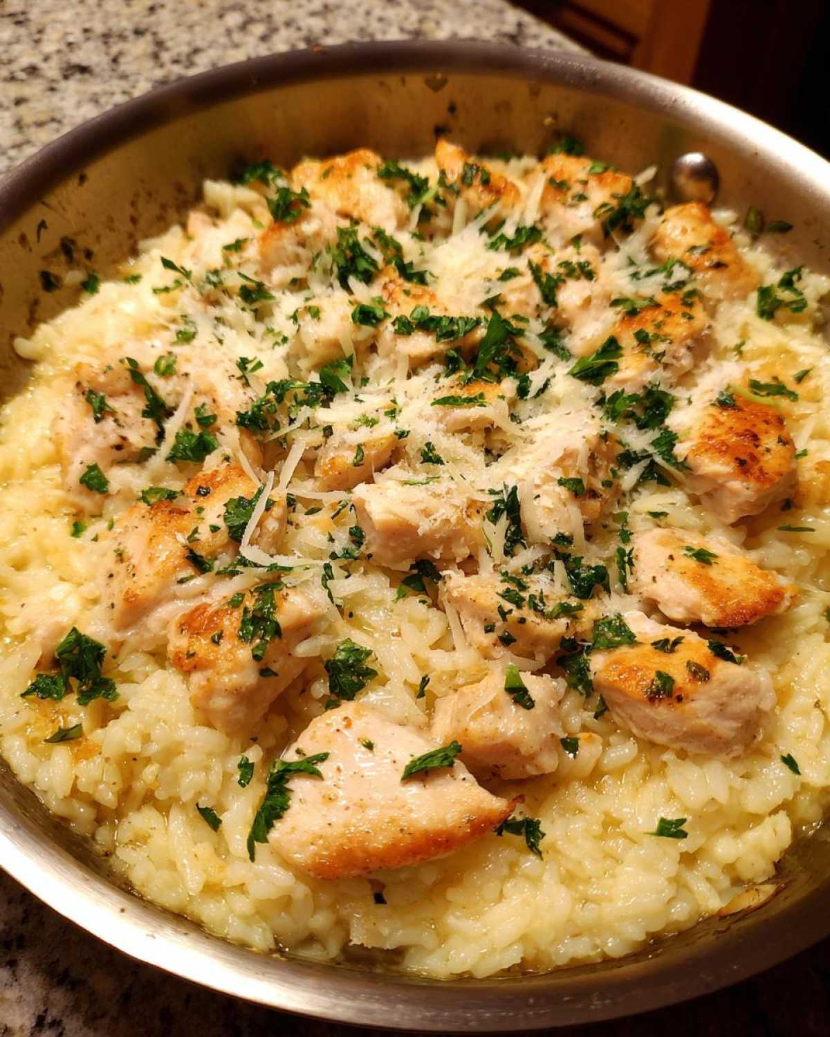 Close-up of Garlic Butter Rice with Chicken Skillet topped with Parmesan and parsley in a metal pan.