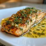 A beautifully cooked fillet of Garlic Butter Salmon with Lemon Herb Sauce, glistening with melted butter and fresh herbs.