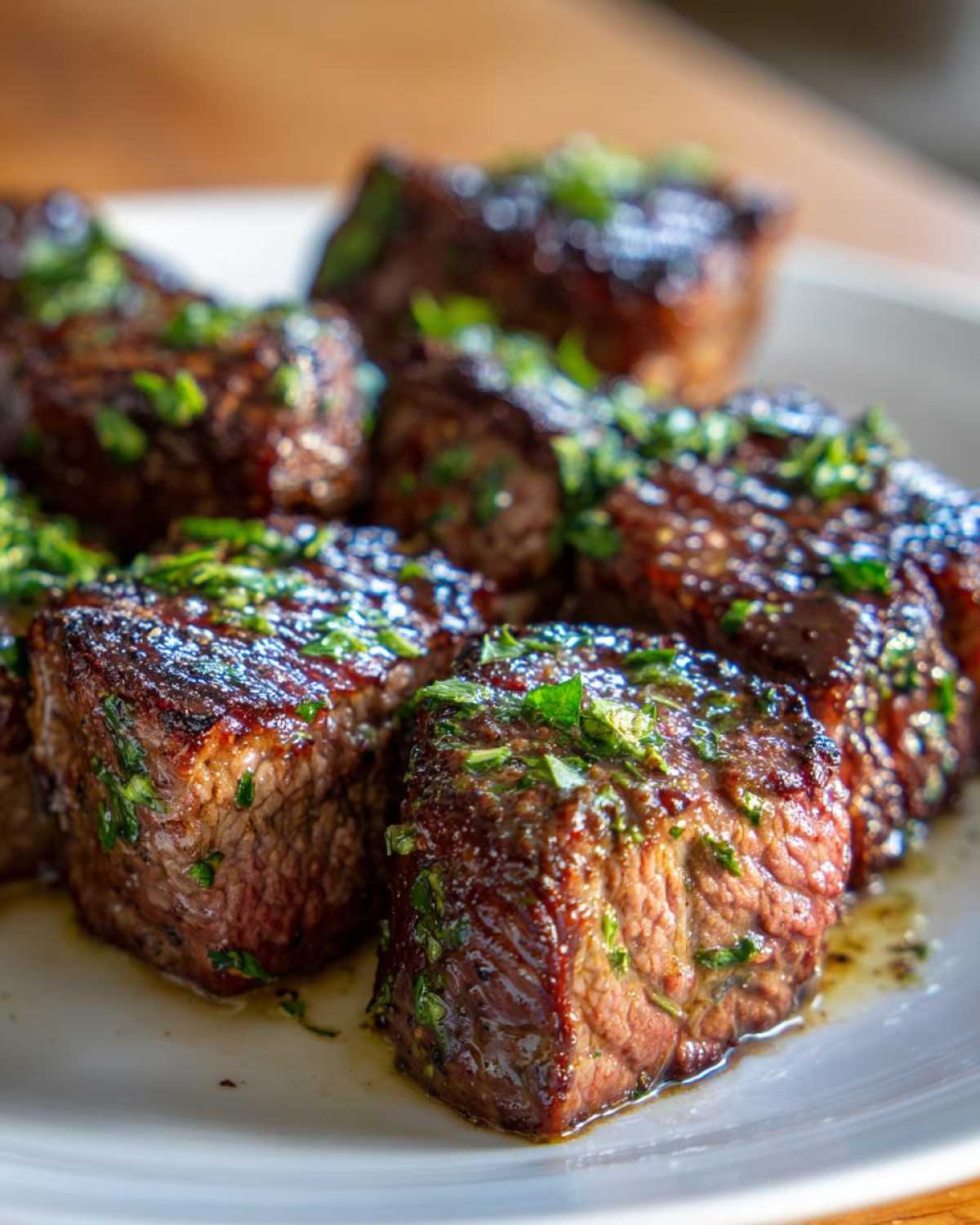 Close-up of perfectly cooked Garlic Butter Steak Bites with a juicy center, glistening with butter sauce and topped with fresh parsley.