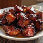 Close-up of shiny, caramelized Honey Garlic Salmon Bites piled on a white plate.