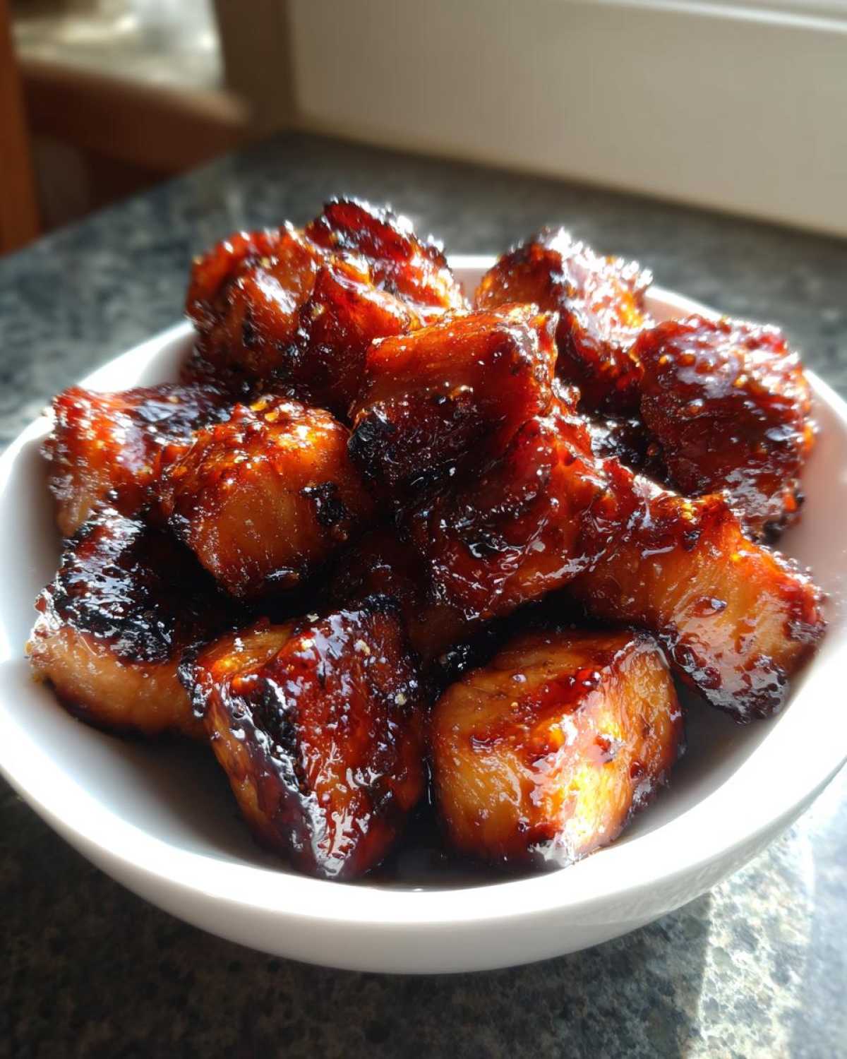 Close-up of Honey Garlic Salmon Bites with caramelized edges piled in a small white bowl.