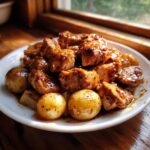 Close-up of Honey Mustard Chicken Skillet with Potatoes coated in a glossy sauce on a white plate.