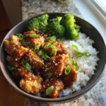 A close-up of a Honey Soy Chicken Bowl Quick Dinner Idea featuring glazed chicken pieces over white rice with steamed broccoli.