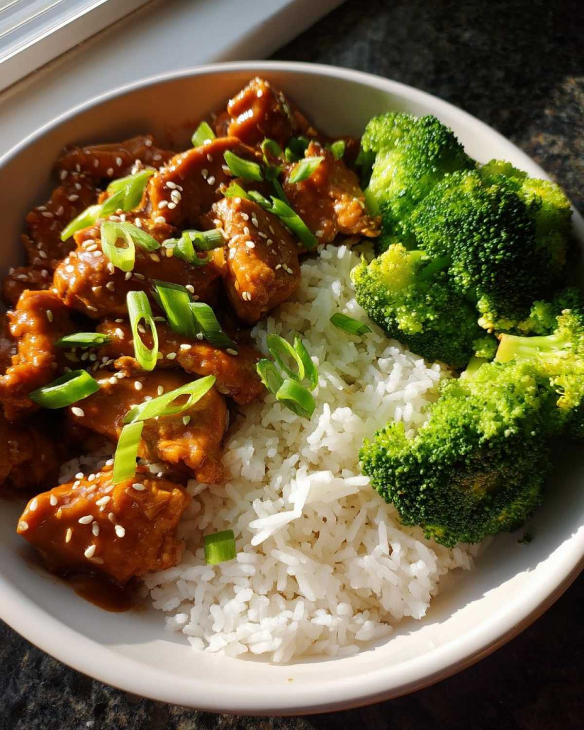 A bowl featuring Honey Soy Chicken Bowl Quick Dinner Idea served over white rice with steamed broccoli florets.