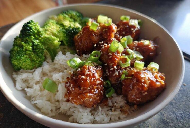 A close-up of a Honey Soy Chicken Bowl featuring glazed chicken pieces, white rice, and steamed broccoli, topped with green onions.