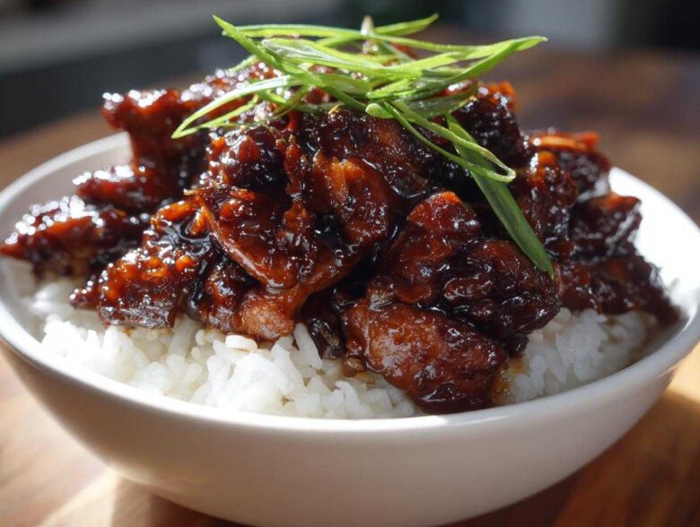 Close-up of Honey Soy Garlic Chicken with a thick, dark glaze served over fluffy white rice and garnished with green onions.