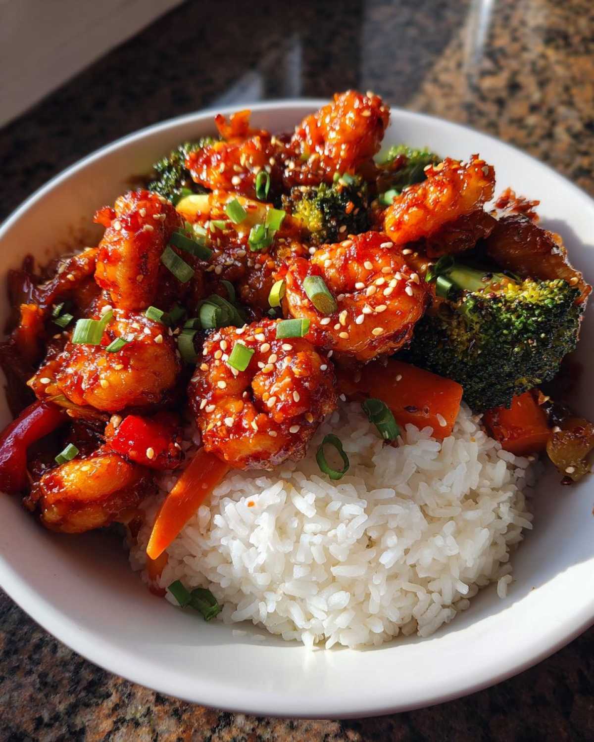 Close-up of a Honey Sriracha Shrimp Bowl with rice, broccoli, and sesame seeds.
