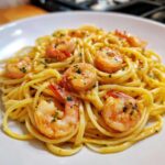A close-up of a white bowl filled with Lemon Butter Shrimp Pasta Ready in 20 Minutes, garnished with parsley.