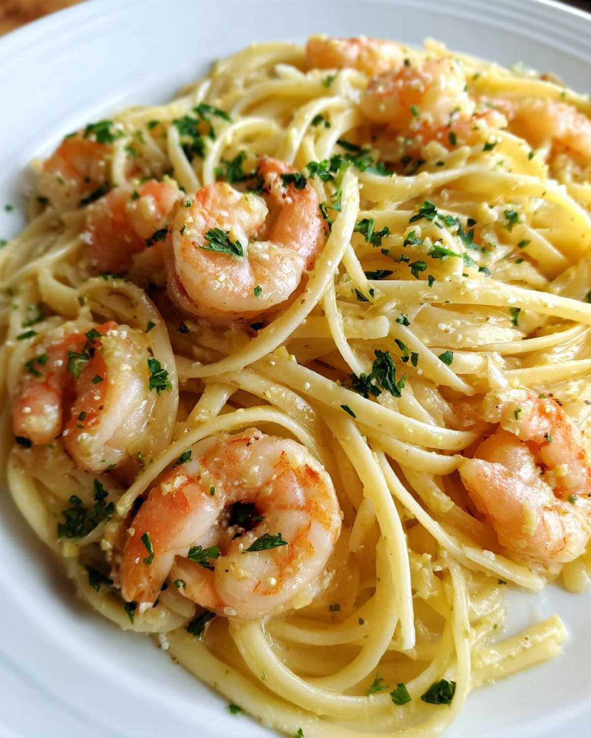 Close-up of a serving of Lemon Butter Shrimp Pasta Ready in 20 Minutes, featuring linguine coated in sauce and topped with pink shrimp and parsley.