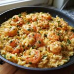 Close-up of creamy Lemon Garlic Shrimp Orzo One Pan Dinner garnished with fresh parsley in a dark skillet.
