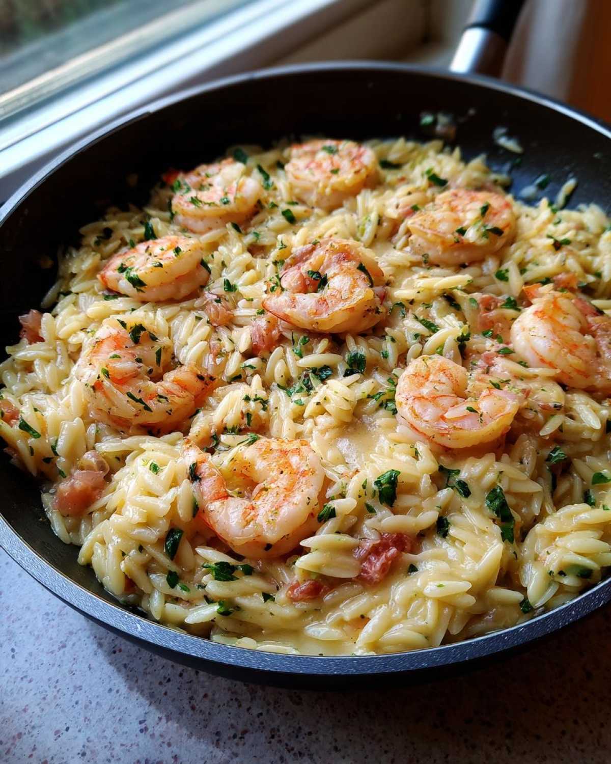 Close-up of creamy Lemon Garlic Shrimp Orzo One Pan Dinner topped with perfectly cooked shrimp and fresh parsley.