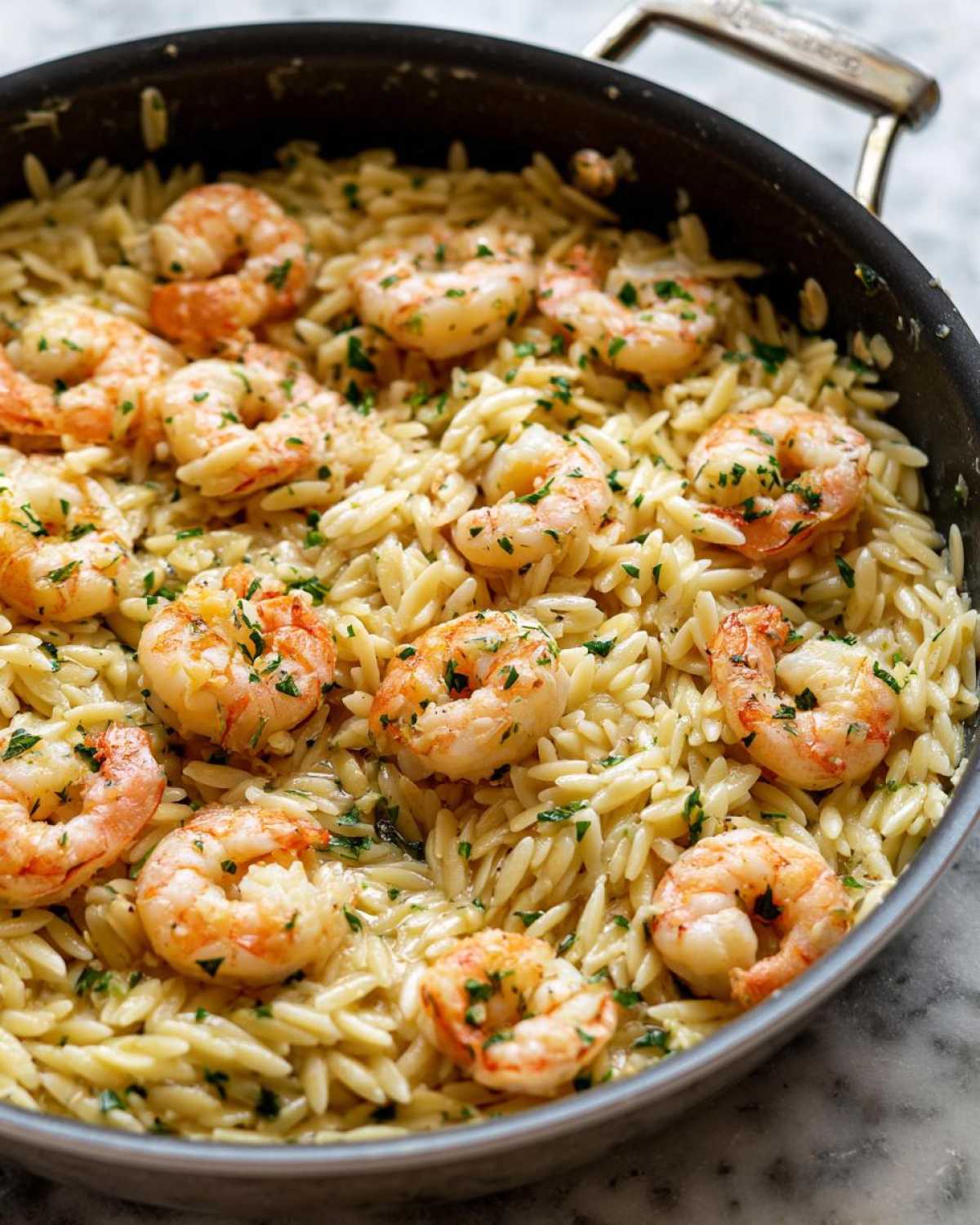 Close-up of Lemon Garlic Shrimp Orzo one pan dinner cooked in a skillet, topped with fresh parsley.