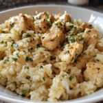 Close-up of a white bowl filled with creamy Garlic Butter Chicken and Rice, topped with fresh parsley.