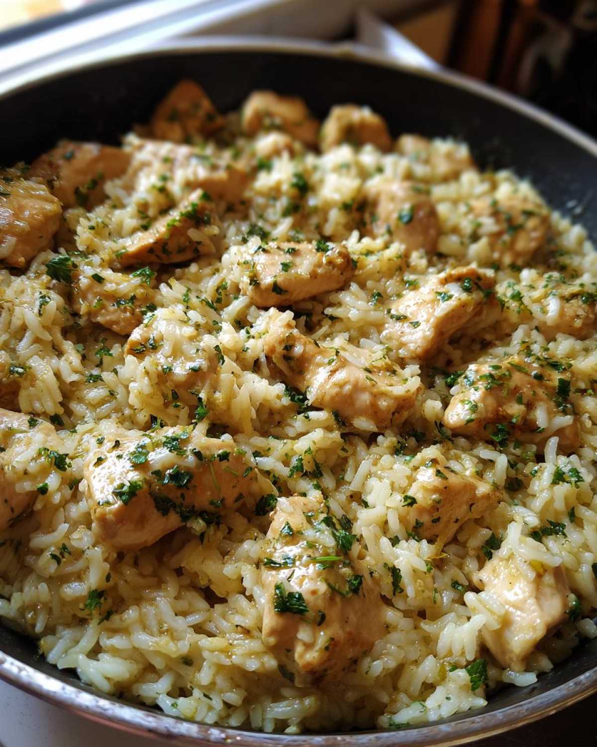 Close-up of Garlic Butter Chicken and Rice One Pot Dinner cooked in a skillet, topped with parsley.