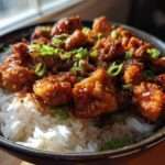 Close-up of Sticky Sweet Chili Chicken Skillet pieces coated in sauce served over white rice and garnished with green onions.