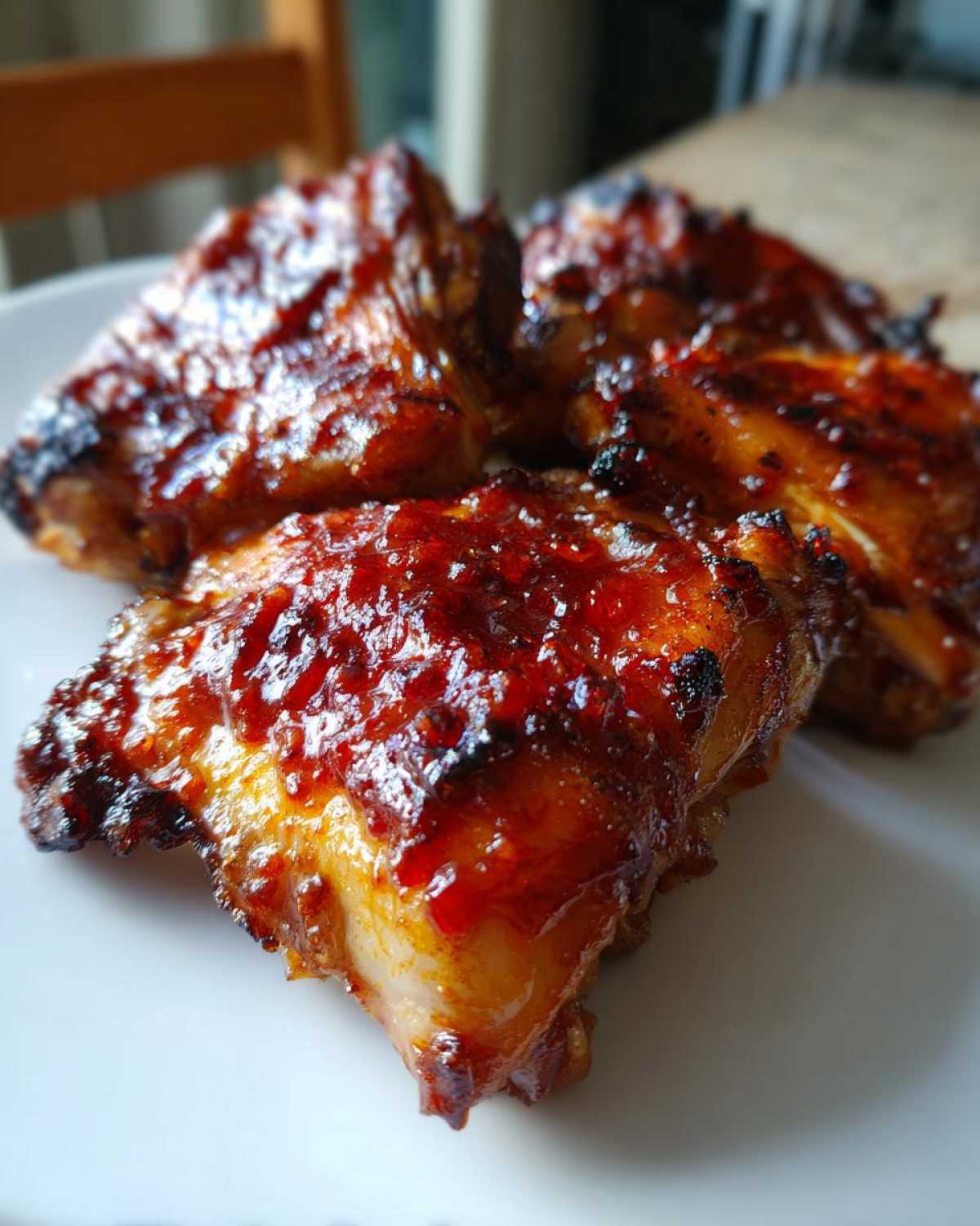 Close-up of four oven baked Sticky Sweet Chili Chicken Thighs with a glossy, caramelized glaze.