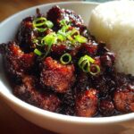 Close-up of Sticky Teriyaki Chicken Easy Weeknight Meal coated in dark glaze, served with white rice and green onions.