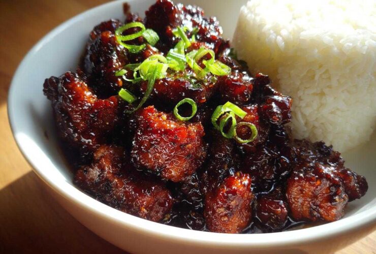 Close-up of Sticky Teriyaki Chicken Easy Weeknight Meal coated in dark glaze, served with white rice and green onions.
