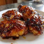 Three pieces of glistening Sticky Teriyaki Chicken Thighs with Garlic coated in a thick, dark glaze.