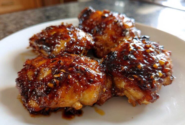 Three pieces of glistening Sticky Teriyaki Chicken Thighs with Garlic coated in a thick, dark glaze.