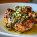 Close-up of perfectly browned Baked Chicken Thighs with Garlic Butter Sauce, glistening with butter and topped with minced garlic and parsley.