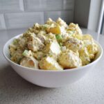 A large white bowl overflowing with creamy, chunky Chick-fil-A Potato Salad featuring potatoes, celery, and eggs.